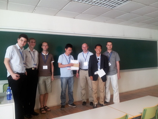 Photograph of organisers (Valentin Robu, Colin R. Williams and Enrico H. Gerding) presenting the teams of joint third place winners (Siqi Chen, Gerhard Weiss, Alex Dirkzwager and Mark Hendrikx) with their prizes.